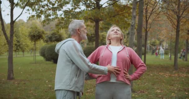 Entraîneur de fitness personnel aidant la femme âgée, faisant de l'exercice d'étirement — Video