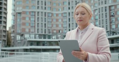 Emekli kadın müteahhit tablet üzerinde notlar alıyor, yeni gayrimenkul değerlendirmesi yapıyor.