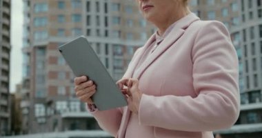 Yeni gökdelen yakınlarında tablet üzerinde çalışan emlakçı, uygun fiyatlı ipotekler.