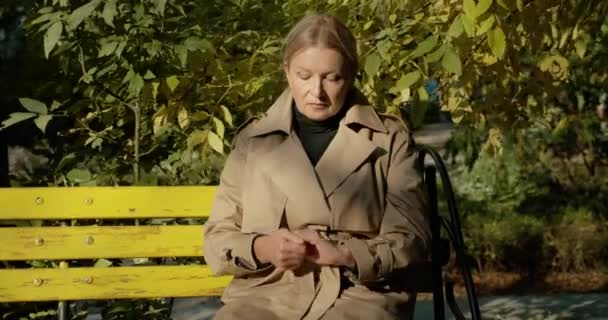 Ümitsiz yaşlı bayan parkta tek başına oturuyor, nişan yüzüğünü çıkarıyor, boşanıyor. — Stok video