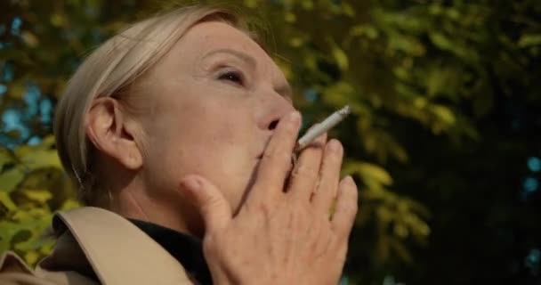 Donna bionda matura che fuma sigarette nel parco, cattive abitudini, stile di vita malsano — Video Stock