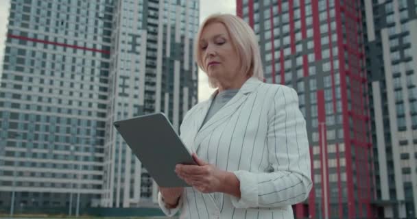 Broker immobiliare femminile che lavora su tablet vicino a complesso residenziale, business — Video Stock