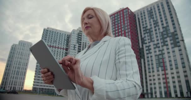 Lady chefe digitando em tablet perto de complexo residencial, compra de apartamento, aluguel — Vídeo de Stock