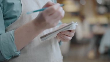 Garson restoranda sipariş veriyor, not defterine yazıyor, iş sorumlulukları...