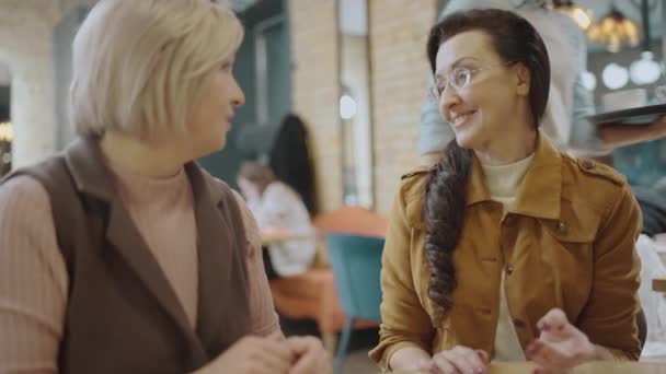 Офіціантка, що подає чай жінкам-клієнтам у кафе, кладе чашки на стіл — стокове відео