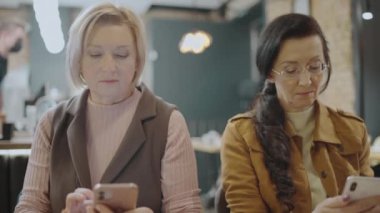 Kadınlar akıllı telefondan fotoğraf çekiyor, çay içiyor, alet bağımlısı oluyor, rahatlıyor.