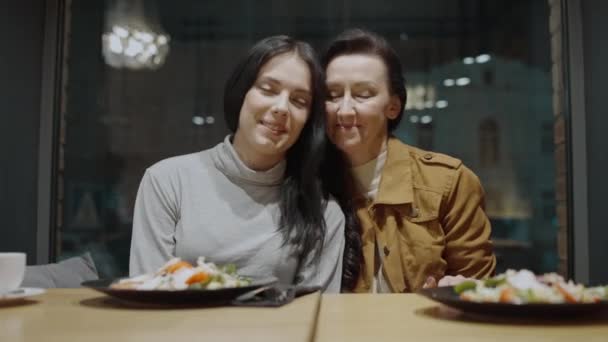 Usmívající se mladá žena a matka dotýkající se hlav, dívající se na kameru, rodina láska — Stock video
