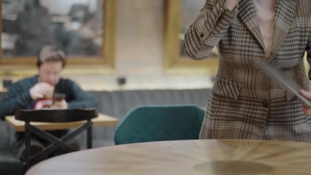 Ocupada mujer de negocios hablando por teléfono, sentada en la mesa del restaurante con portátil — Vídeos de Stock