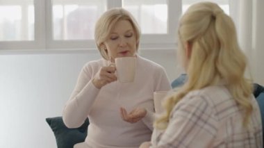 Gülümseyen anne kızıyla iletişim kuruyor, birlikte kahve içiyor, aile kuruyor.