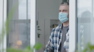 Korumalı maskeli bir memur pencerenin yanında duruyor, koronavirüs salgını.