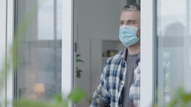 Korumalı maskeli bir memur pencerenin yanında duruyor, koronavirüs salgını.