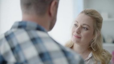 Sarışın, güzel bir kadın. Sarılan bir erkek, şefkatli bir eş. Kocayı destekleyen bir birliktelik.