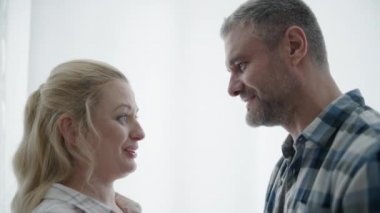 Mutlu evli çift göbeğini okşuyor, birbirine bakıyor, mutlu ebeveynlik yapıyor.