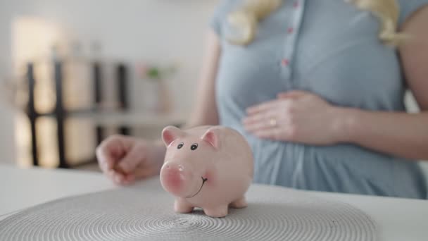 Pregnant female putting coin in piggybank on table, bank investment, savings — Stock Video