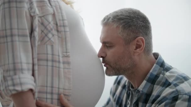 Opgewonden man knuffelen zwangere vrouw, kussen buik, prenatale binding met baby — Stockvideo