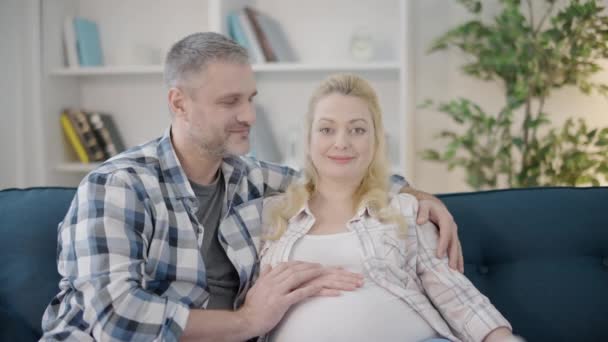 Esposo cariñoso y esposa embarazada abrazando, sonriendo a la cámara, relación feliz — Vídeo de stock