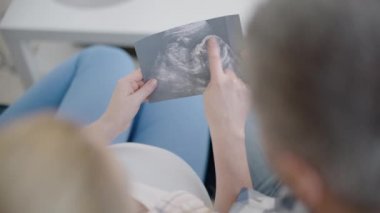 Erkek ve kadın birlikte hamilelik taramasına bakıyor, ebeveynlik hazırlığı