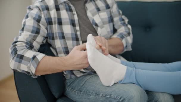 Relaxing pregnant wife talking on phone, lying on sofa, husband massaging feet — Stock Video