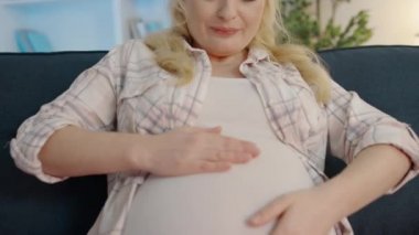 Neşeli müstakbel anne karnını okşuyor, bebekle iletişim kuruyor, ilişki kuruyor.