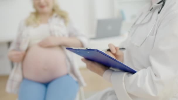 Obstetra con escritura de estetoscopio en portapapeles, consulta de atención prenatal — Vídeos de Stock