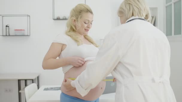 Ginekolog badający brzuch ciężarnej mierząc rozmiar na taśmie, opieki prenatalnej — Wideo stockowe