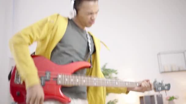若い男でヘッドフォンジャミングで電気ギター お気に入りの趣味 — ストック動画