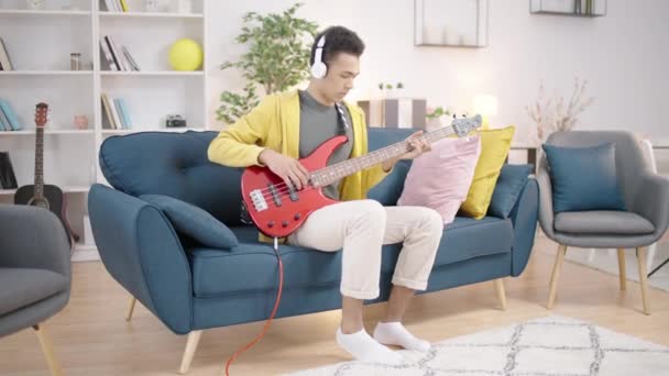Teenager Mit Kopfhörern Lernt Akkorde Spielt Bassgitarre Hause — Stockvideo