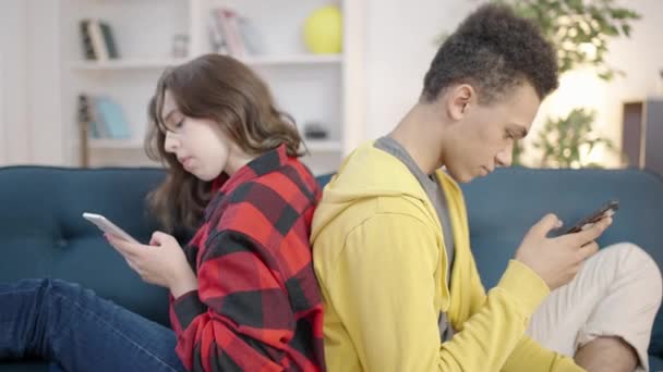一对青少年背靠背地坐在一起 与他们的手机 社交媒体成瘾 — 图库视频影像