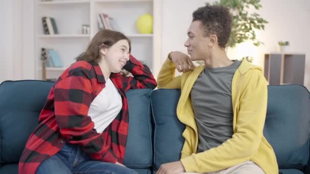 Flirty Interracial Teen Pärchen Sitzt Auf Dem Sofa Und Chattet — Stockvideo