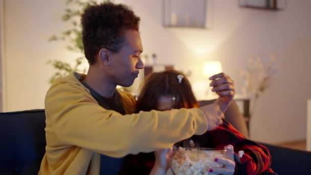 在电视上看完恐怖片中的恐怖场景后 一对有趣的青少年夫妇正在采摘爆米花 — 图库视频影像