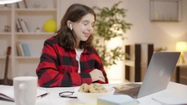 Kulaklıklı genç kız bilgisayar video bağlantısı üzerinden öğretmenle konuşuyor.