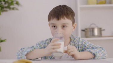 Evde lezzetli sütün tadını çıkaran mutlu bir çocuk, güçlü kemikler, çocuk dişleri, kalsiyum.