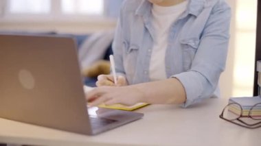 Genç bir bayan not defterinde yabancı dil öğreniyor, online dersler alıyor.
