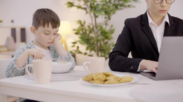 Menino Solitário Sentado Mesa Mãe Trabalhando Digitando Laptop Ignorando Filho — Vídeo de Stock