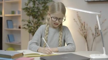 Gözlüklü genç kız günlük tutuyor, ödev yapıyor, uzaklardan öğreniyor.