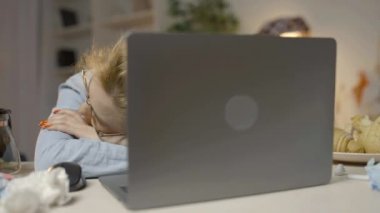 Dağınık bir masada dizüstü bilgisayarla uyuyan serbest çalışan bir kadın.