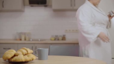 Şişman kadın elinde yoğurt kabı, son kullanma tarihini, kalorilerini kontrol ediyor.