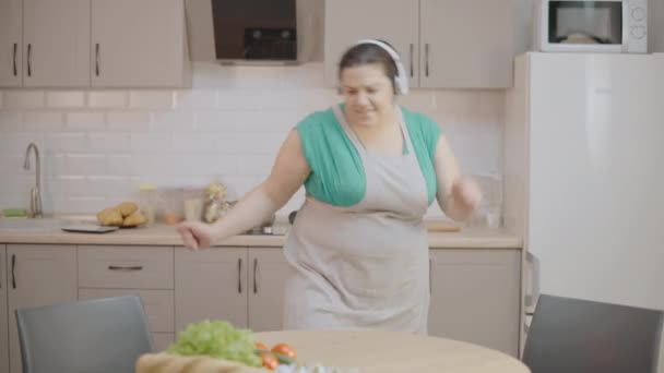 在耳机里唱歌 在家做饭 业余爱好的兴奋的超大女人 — 图库视频影像