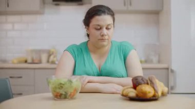 Masada kek ve salata, yemek seçimi, diyet isteyen düşünceli tombul kadın.