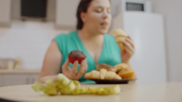 プラスサイズの女性は テーブルの上にテープを測定し クロワッサンを食べる障害を食べる — ストック動画