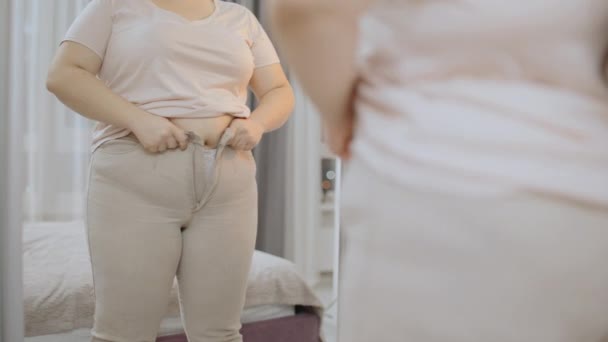 Otyła Kobieta Próbuje Zapiąć Ciasne Spodnie Przed Lustrem Rozmiar — Wideo stockowe