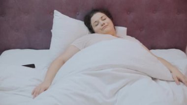 Stresli genç bir kadın akıllı telefon alarmına bakıyor. Sabahları koşuşturuyor.