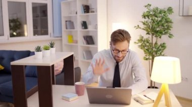 Kravatlı ve şortlu bir şirket çalışanı dizüstü bilgisayarı kapatıyor, karantina sırasında çalışıyor.