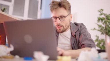 Kirli çamaşırları olan pis uzaktan kumandalı bir çalışan laptopta çalışıyor, çöplerin arasında, kaos içinde.
