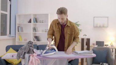 Bekar adam evdeki tahtayı ütülüyor, ev idaresi, rutin işler.