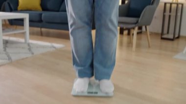 Yeşil elma yiyen, terazinin üzerinde duran, sağlıklı beslenen iri yarı, mutlu bir adam.