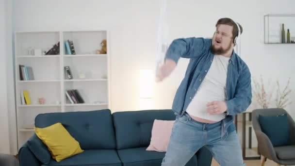 Kulaklıklı Komik Obez Erkek Elektrikli Süpürgeyle Dans Ediyor Şarkı Dinliyor — Stok video