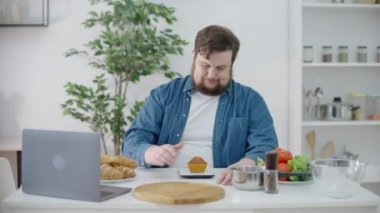 Masadaki keklere bakan üzgün tombul adam, kötü karbonhidratlar, yemek seçimi, diyet.