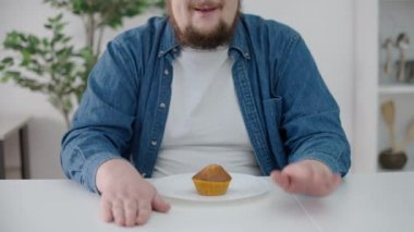 Obez adam mutfak masasında keke bakıyor, şeker hastalığı riski, şeker bağımlılığı