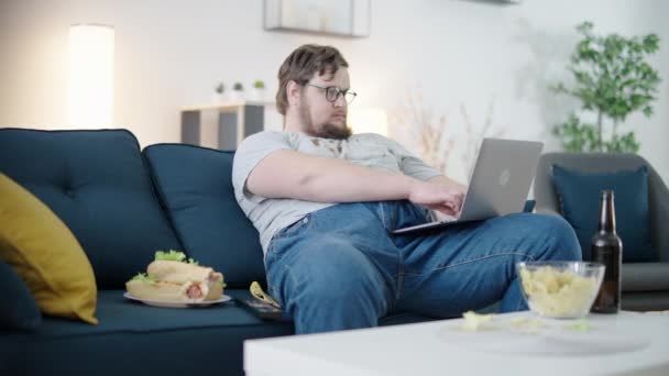 Nieostrożny Mężczyzna Freelancer Brudnych Ubraniach Pracuje Online Jedząc Śmieciowe Jedzenie — Wideo stockowe